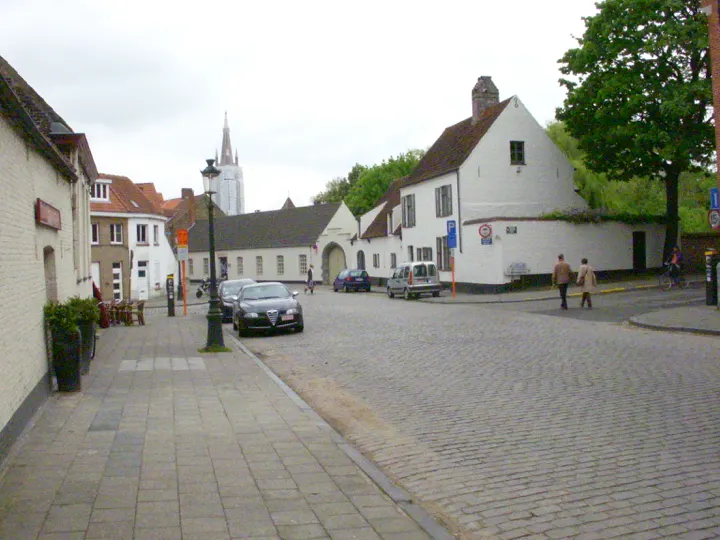 A cobbled street of white houses below a spire