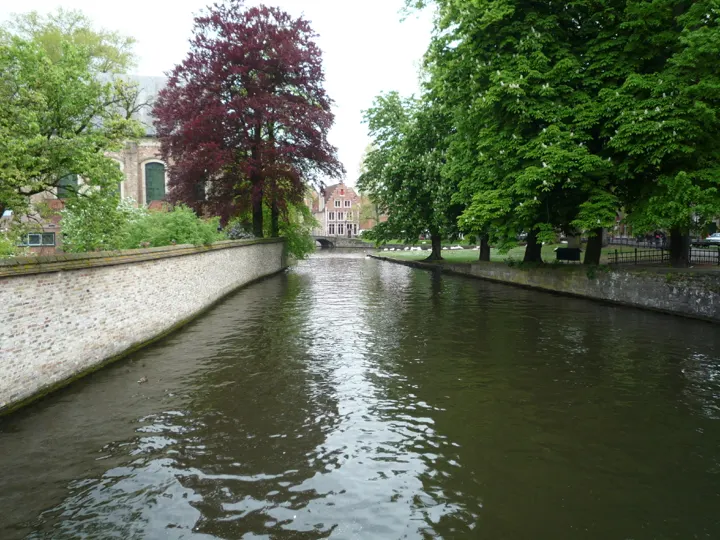 A canal between a white wall and a lawn